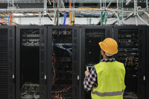 Young technician man working with tablet inside big data center