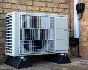 Air source heat pump outside of a brick house